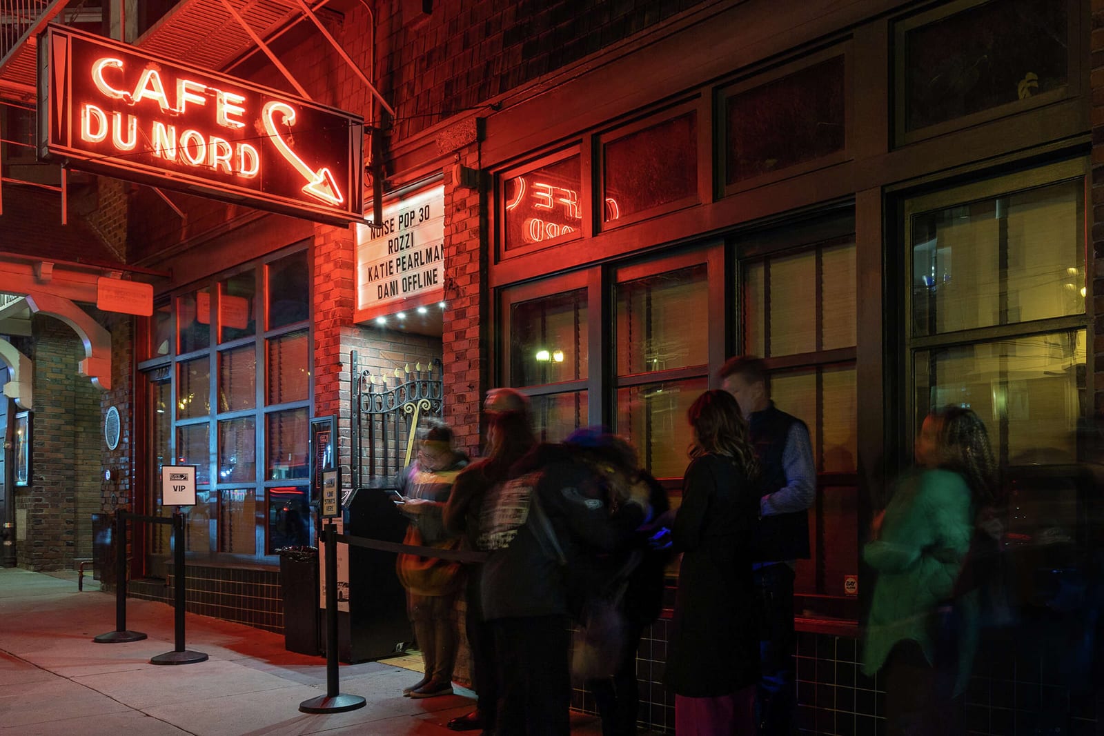 The red Cafe du Nord neon sign over the Market St door at night, with people lined up to go in